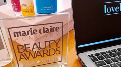 Marie Claire Beauty Awards display with cosmetic products next to a laptop showing the Lovebrands logo.