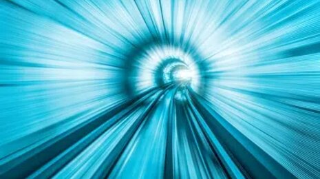 Abstract motion blur of a blue tunnel or light-speed corridor, with converging lines creating a sense of speed, acceleration, and digital or futuristic travel.