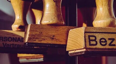 Close-up of wooden stamps, one of which is labeled 'Bezahlt' (Paid in German), symbolizing completed financial transactions