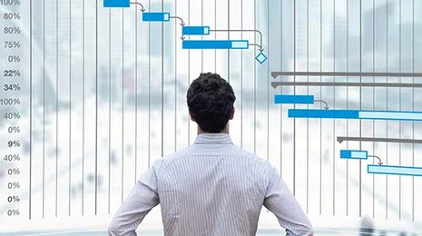 Man in front of a digital Gantt chart showing project timeline, tasks, and progress for management