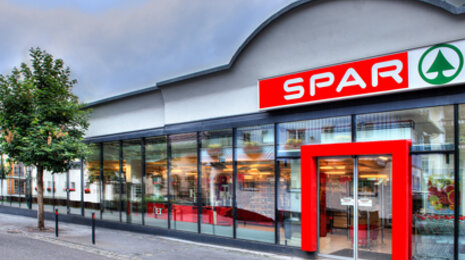 SPAR supermarket exterior with glass fa&ccedil;ade and red entrance signage.