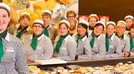 spar bakery staff in uniform standing behind a counter with a display of bread and pastries.
