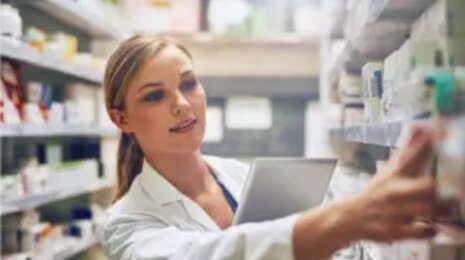 Apothekerin sucht Medikamente in den Regalen