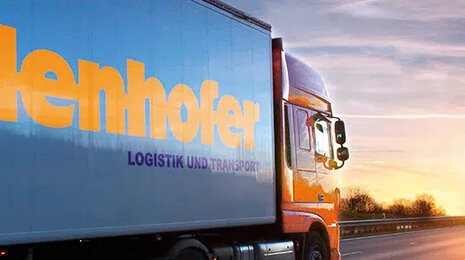Logistics truck with the Hidenhofer branding driving on a highway at sunset, symbolizing transport, logistics services, and on-time delivery.
