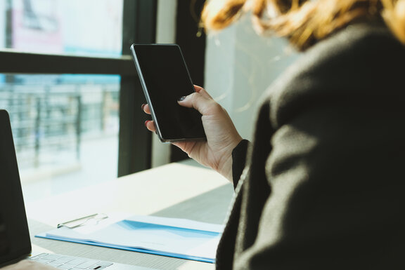 businesswoman holding mobile phone texting message at office