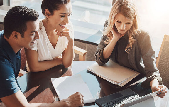 A woman showing another woman and a man something on a tablet