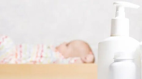 Baby on a bed with lotion and diapers