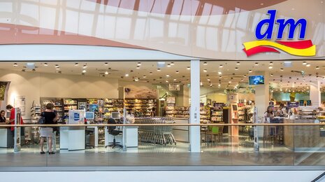 dm drugstore interior with product aisles, checkout area, and customers shopping.