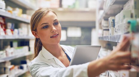 Apothekerin sucht Medikamente in den Regalen