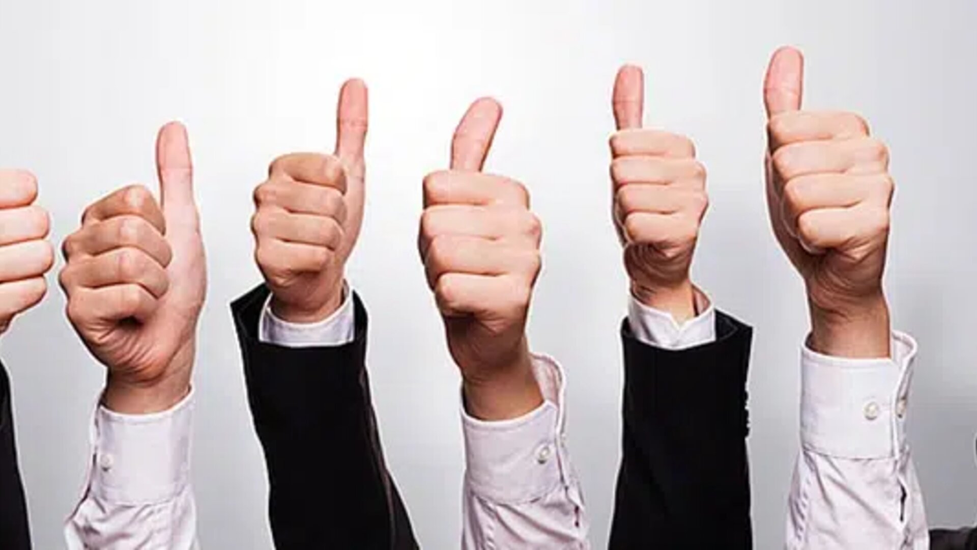 Hands in business attire giving thumbs-up, symbolizing approval, success, or positive feedback