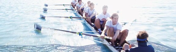 A rowing team working in unison on calm water