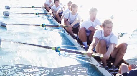 A rowing team working in unison on calm water
