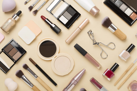 Flat lay with make-up products and tools on a coloured background