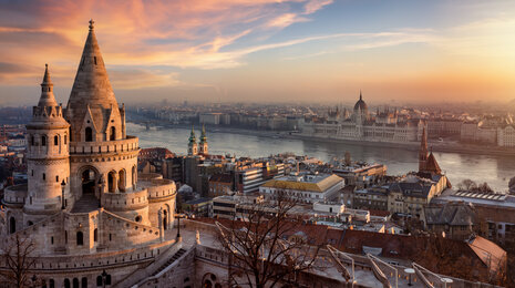 Sunset view of Budapest from Fisherman&rsquo;s Bastion, overlooking the Danube River with the Hungarian Parliament Building and historic cityscape bathed in warm evening light.