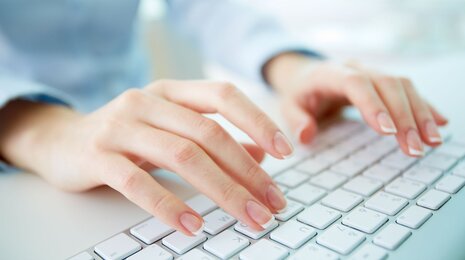 © iStockphoto/shironosov a woman's hands typing on a white computer keyboard, with a bright, softly blurred background