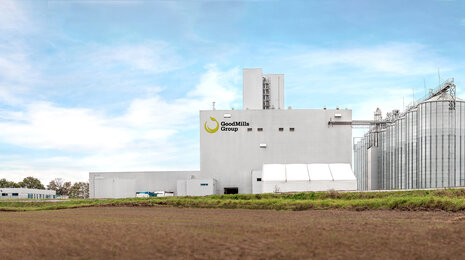 Industrial facility with silos and production buildings under a clear sky.
