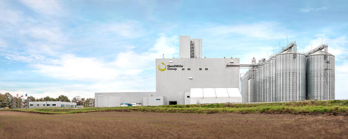 Industrial facility with silos and production buildings under a clear sky.