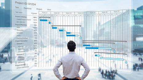 Man in front of a digital Gantt chart showing project timeline, tasks, and progress for management